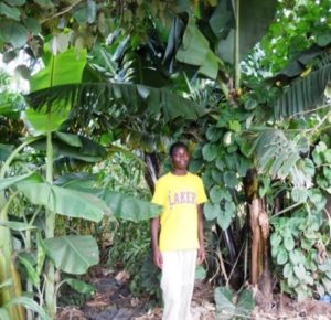 Former Never Ending Food Intern, Hardwell Kaniye, standing in his diversified, organic, and highly-nutritious food forest