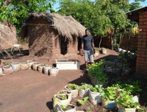 Jacob showing newly established container gardens and solar dryer at his parent's house.
