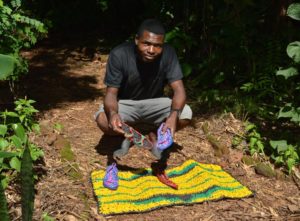 Jacob with shoes and a mat that he made out of recycled plastic